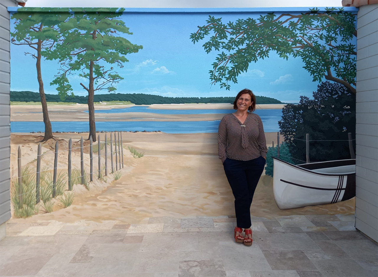 Portrait de Blandine Le Pallec devant sa peinture murale représentant la plage du Veillon, en Vendée. 