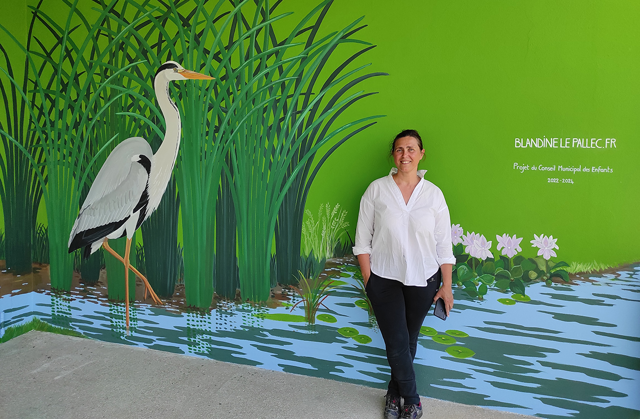 Portrait de Blandine Le Pallec devant sa peinture murale Le Héron, au Poiré sur Vie, Vendée.